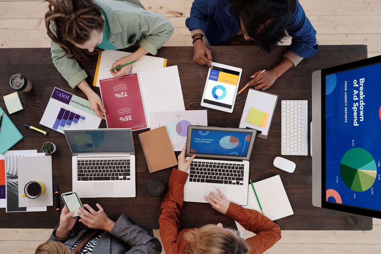 Services A diverse team collaborating on digital marketing strategies at a desk, using laptops and tablets.