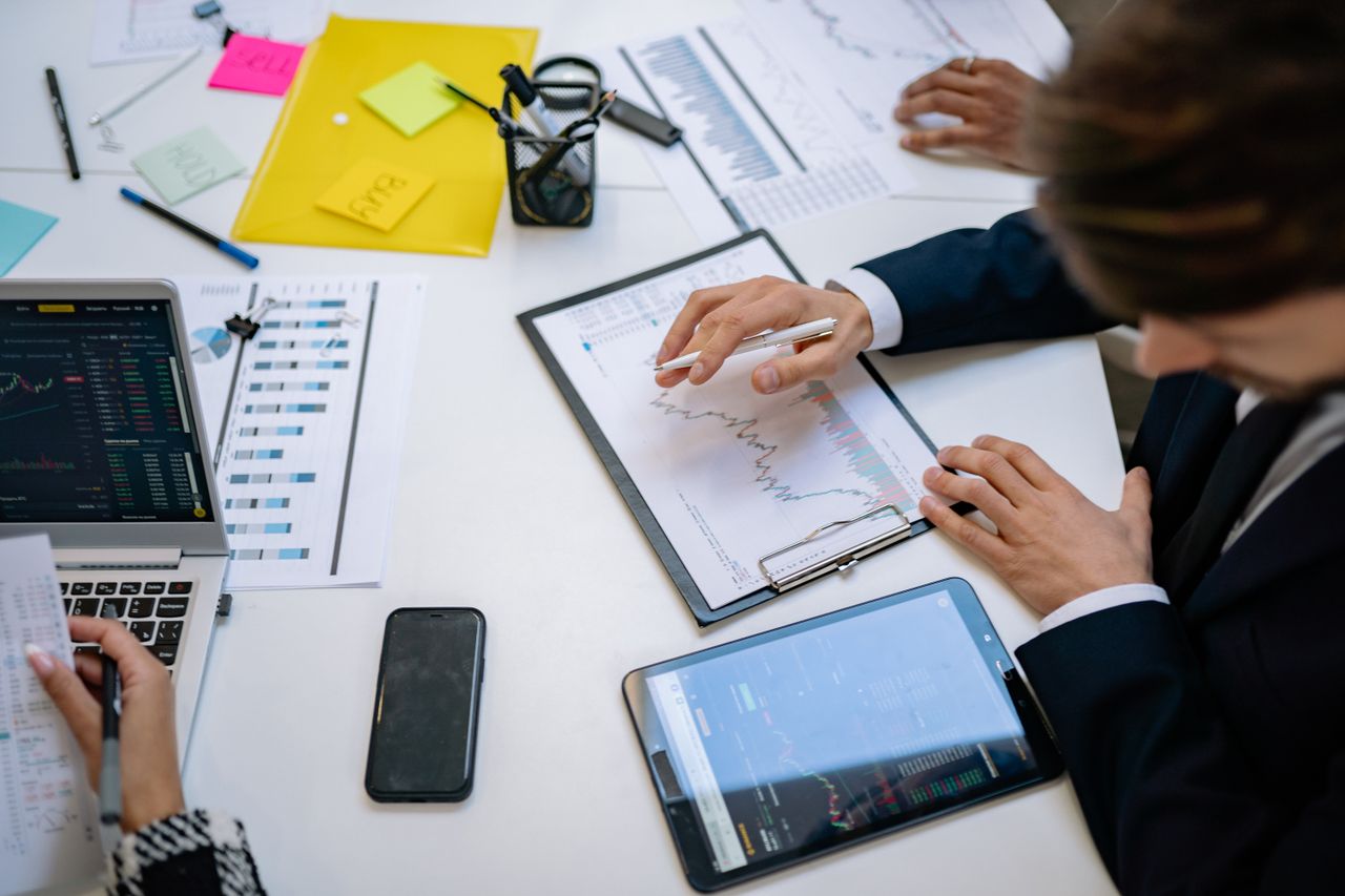 About Team reviewing financial charts and digital data on tablets in an office setting.